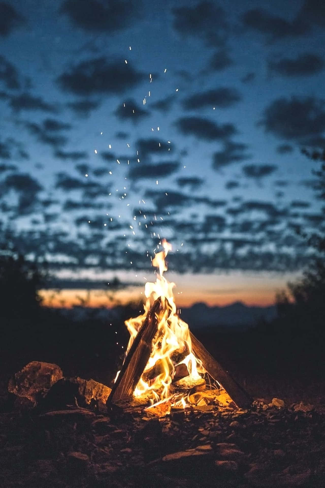 a campfire lit up in the night sky Wallpaper
