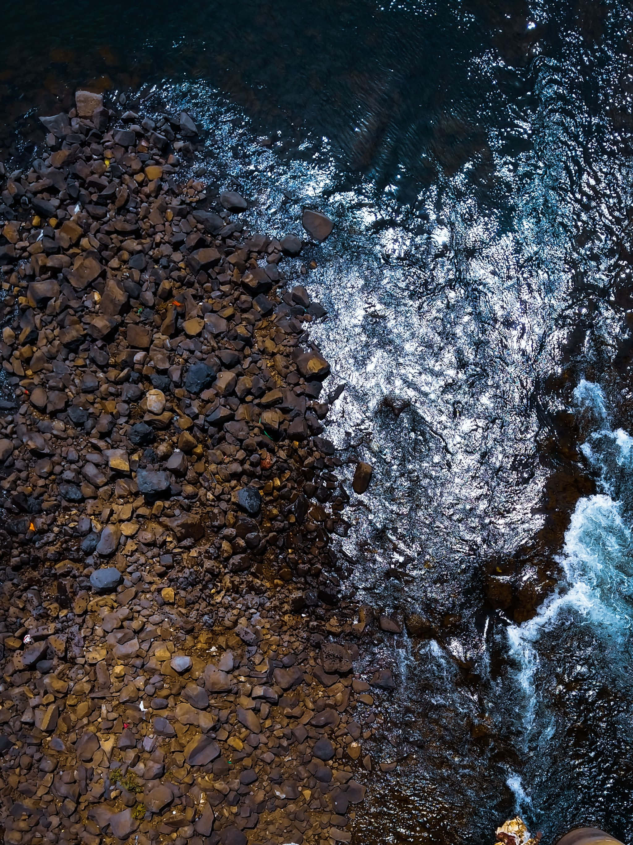 isang lalaki ay nakatayo sa isang talampas na nakatanaw sa tubig Wallpaper