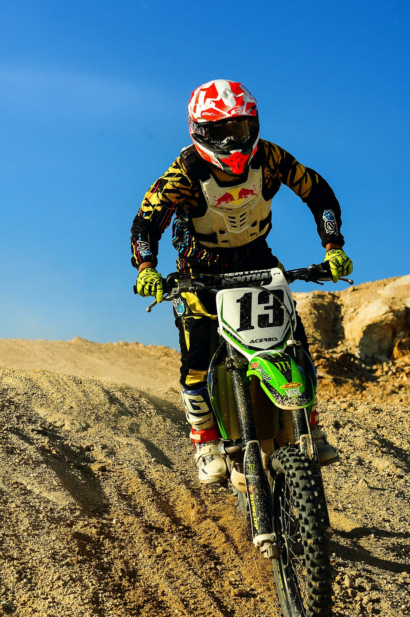 Isang motocross racer na nagtalon ng mataas laban sa isang malinaw na langit Wallpaper
