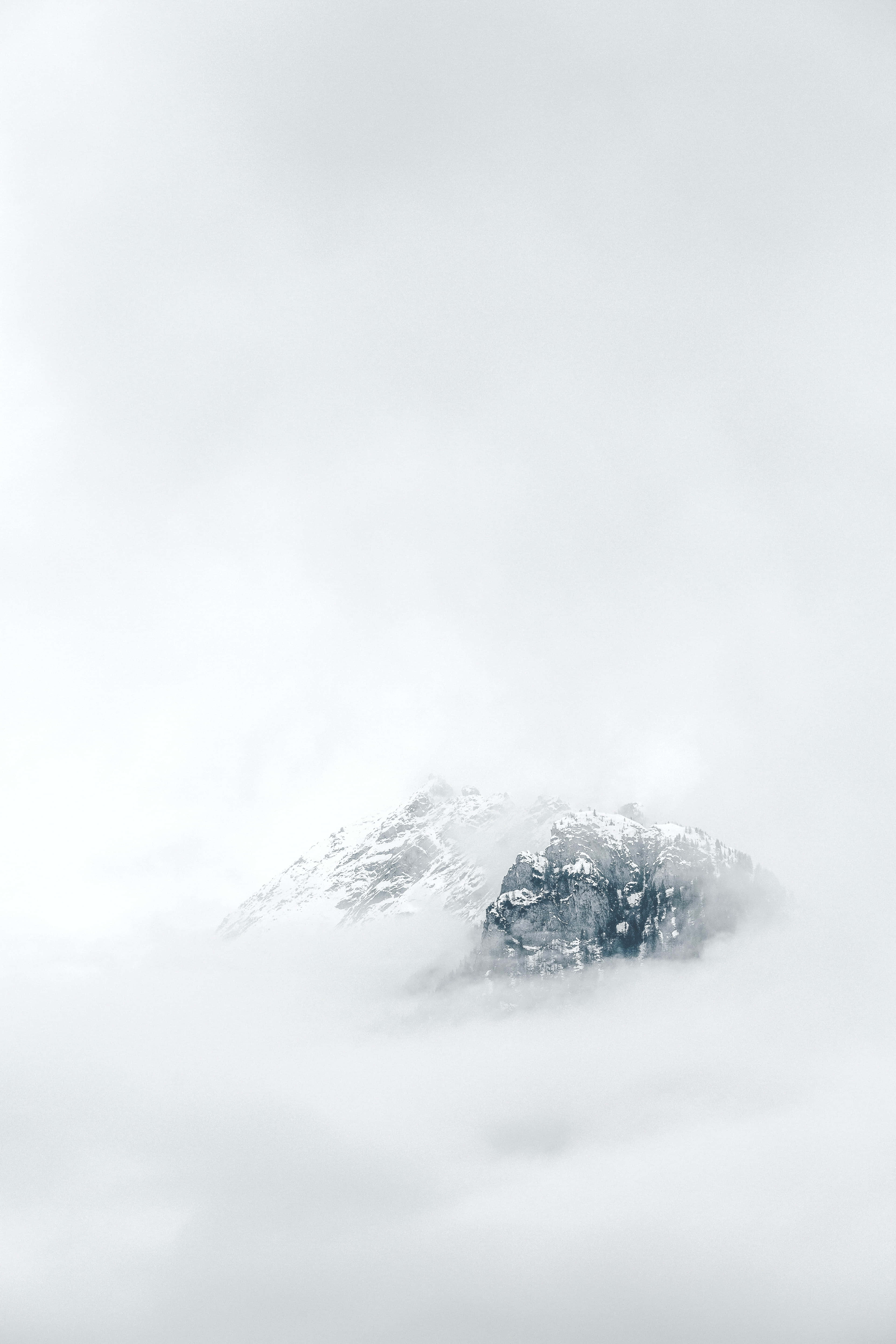 isang bundok na natatakpan ng mga ulap na may niyebe sa itaas Wallpaper