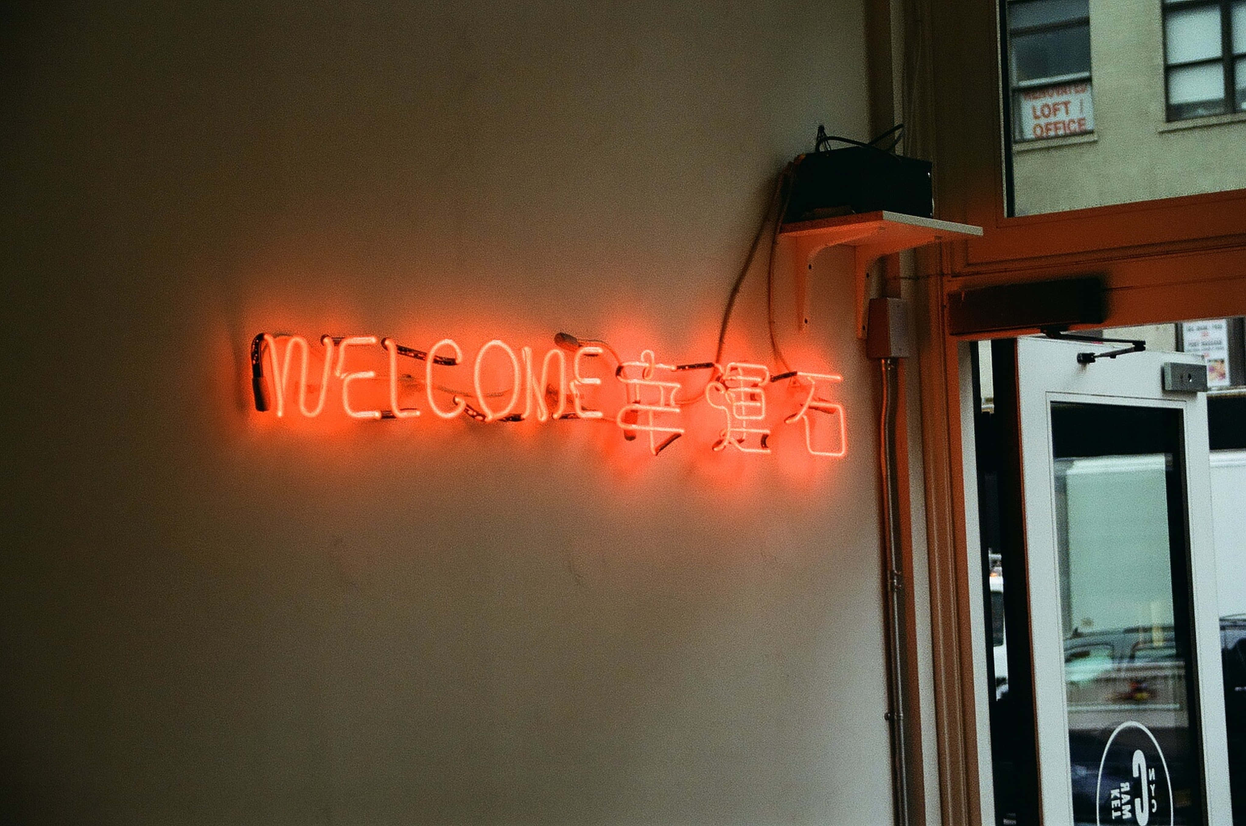 isang neon sign na nagsasabing welcome sa isang pader Wallpaper