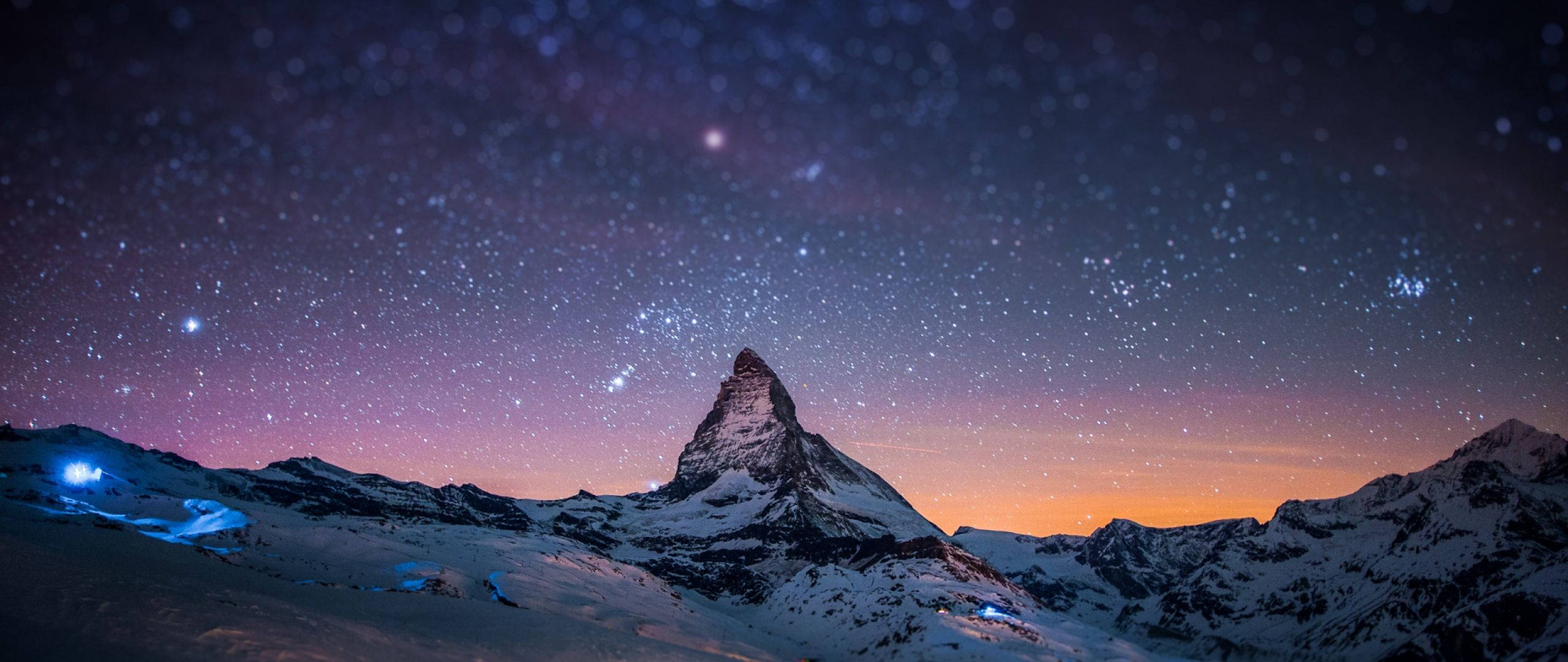 Isang magandang tanawin ng mga bundok na nililiwanagan ng isang pastel galaxy Wallpaper