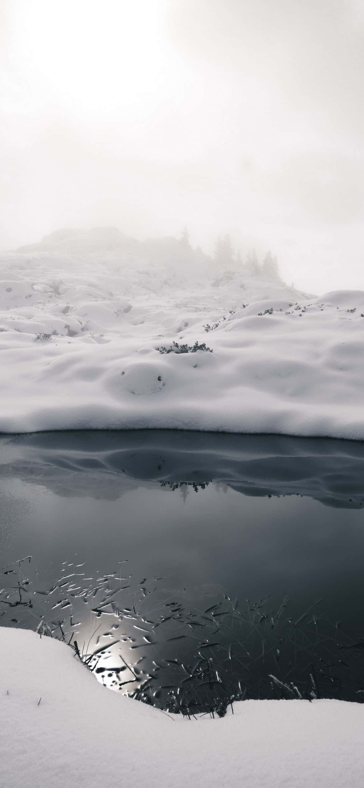 a snow covered lake with a reflection Wallpaper