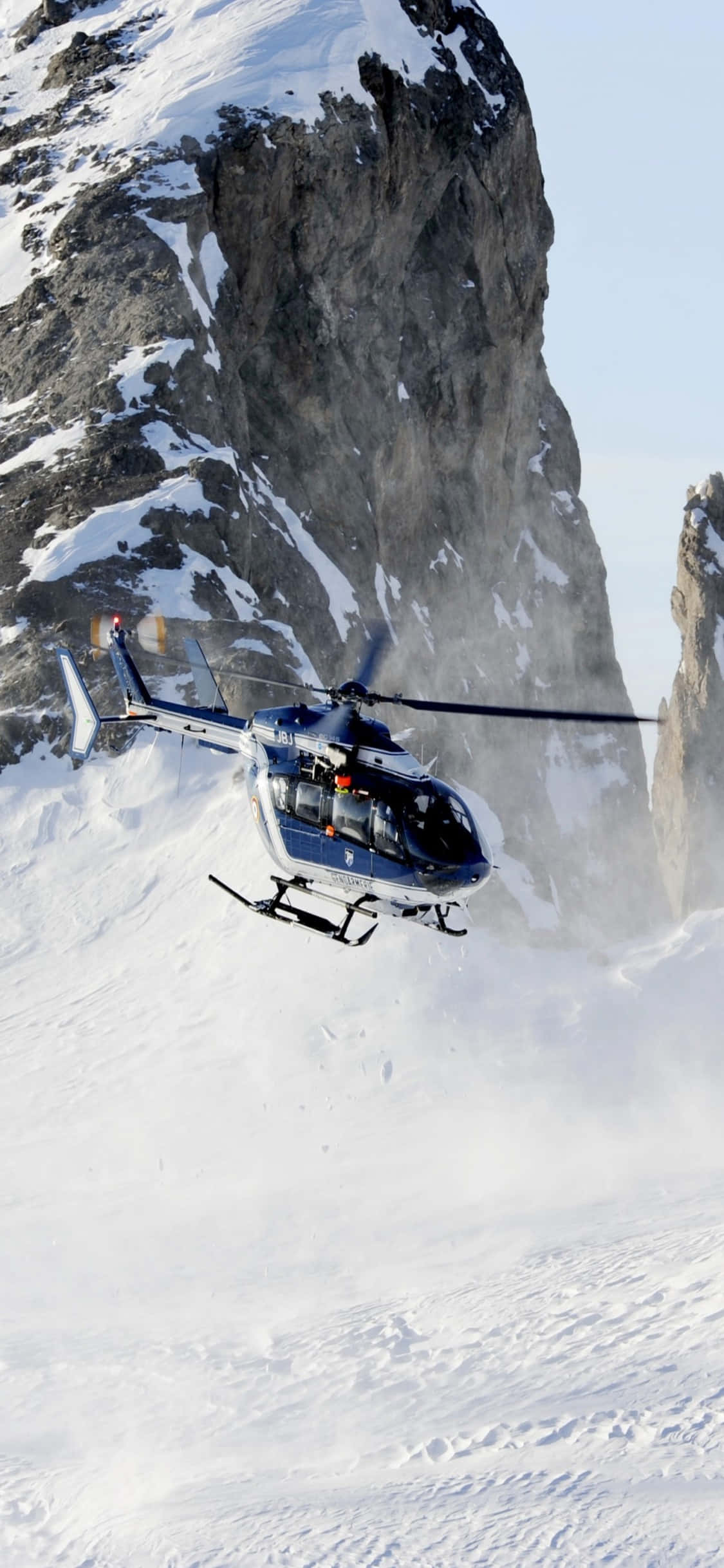Isang nakakagulat na tanaw ng mga Helicopter sa itaas ng isang magandang tanawin, nakuhan sa isang iPhone Xs Wallpaper