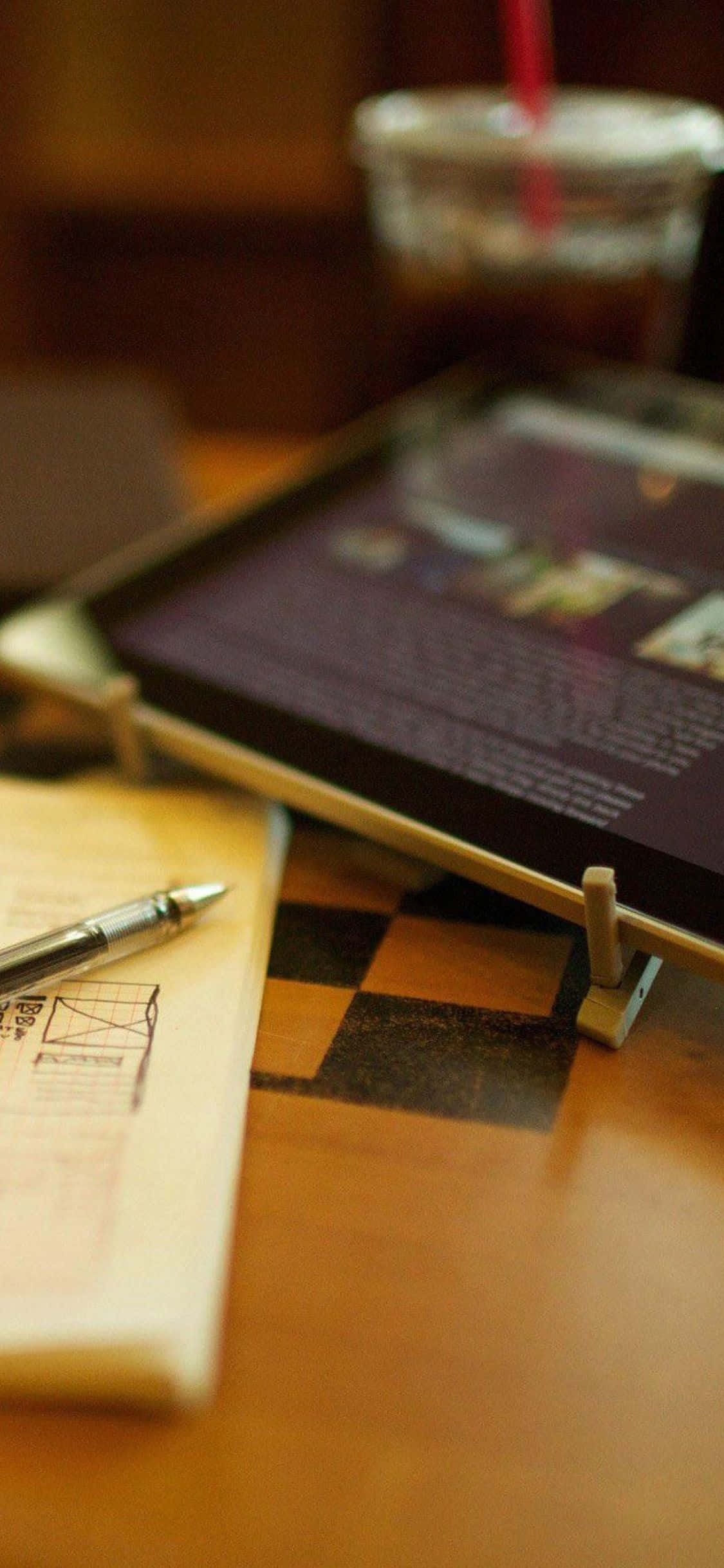 Isang masiglang estasyon ng trabaho na nagtatampol ng Apple iPhone Xs na nagpapaganda sa isang makinis at modernong desk. Wallpaper