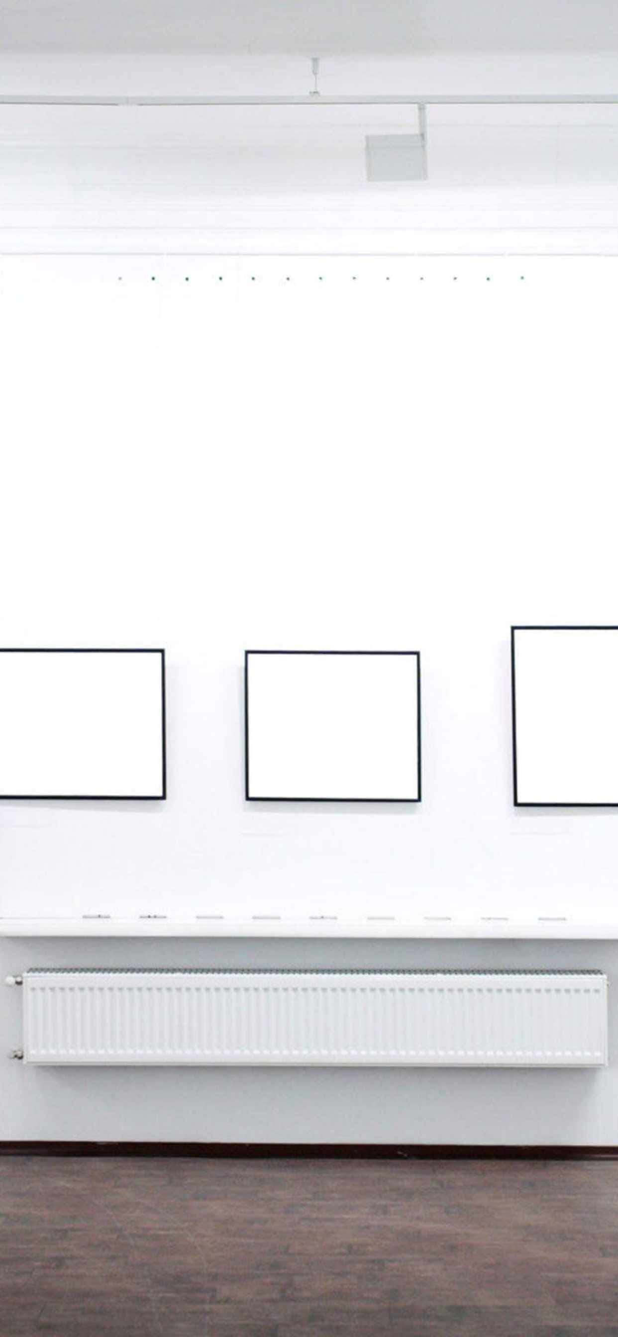 isang puting kwarto na may ilang blank framed pictures Wallpaper