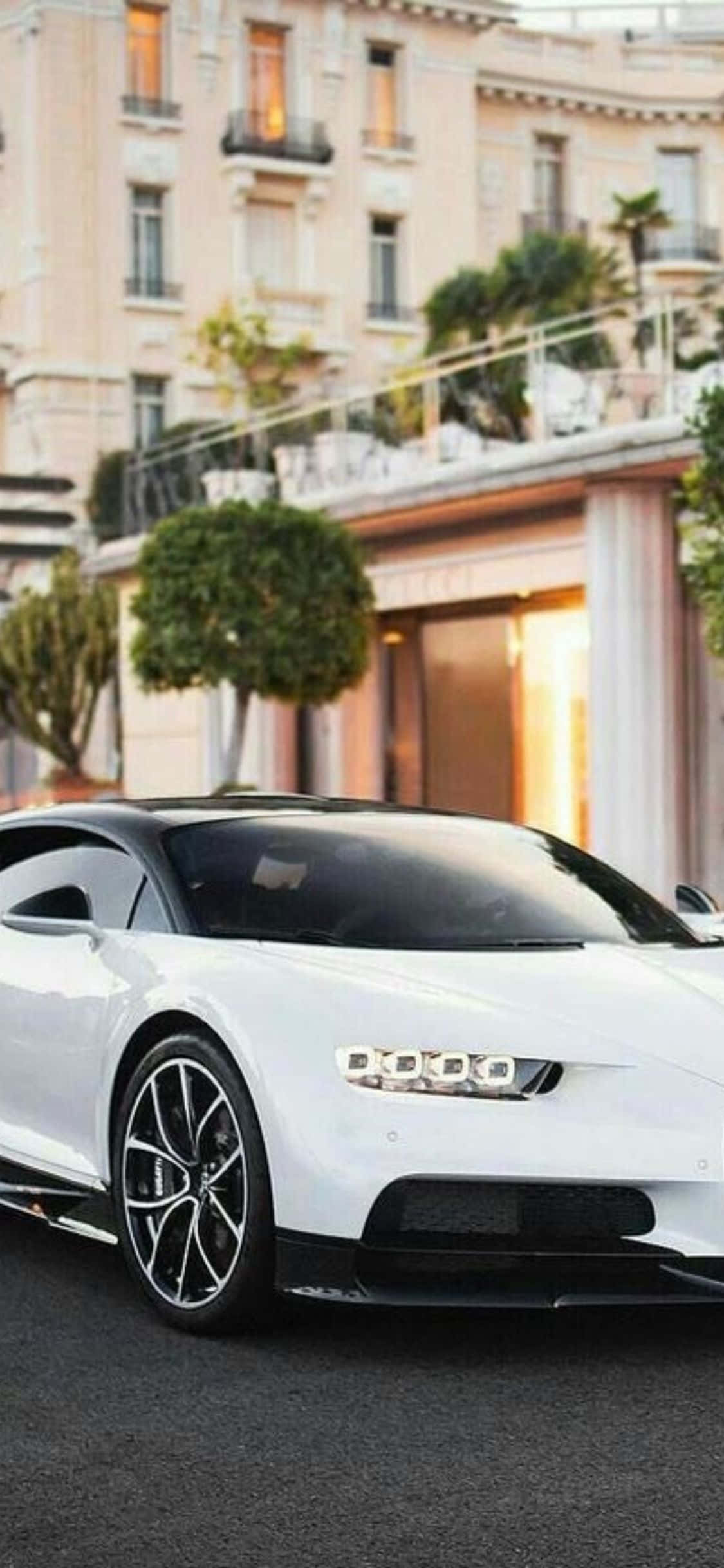 ang puting bugatti chiron ay nakaparada sa harap ng isang building Wallpaper