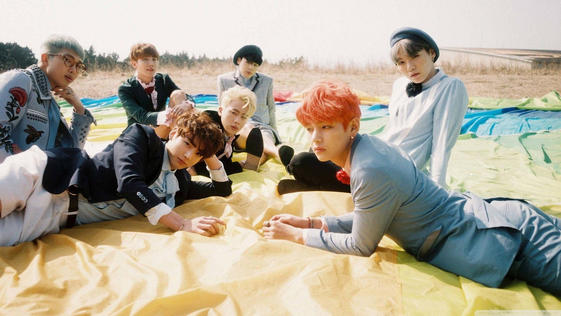 BTS Members Nakahiga Sa Field Gamit ang Laptop Wallpaper