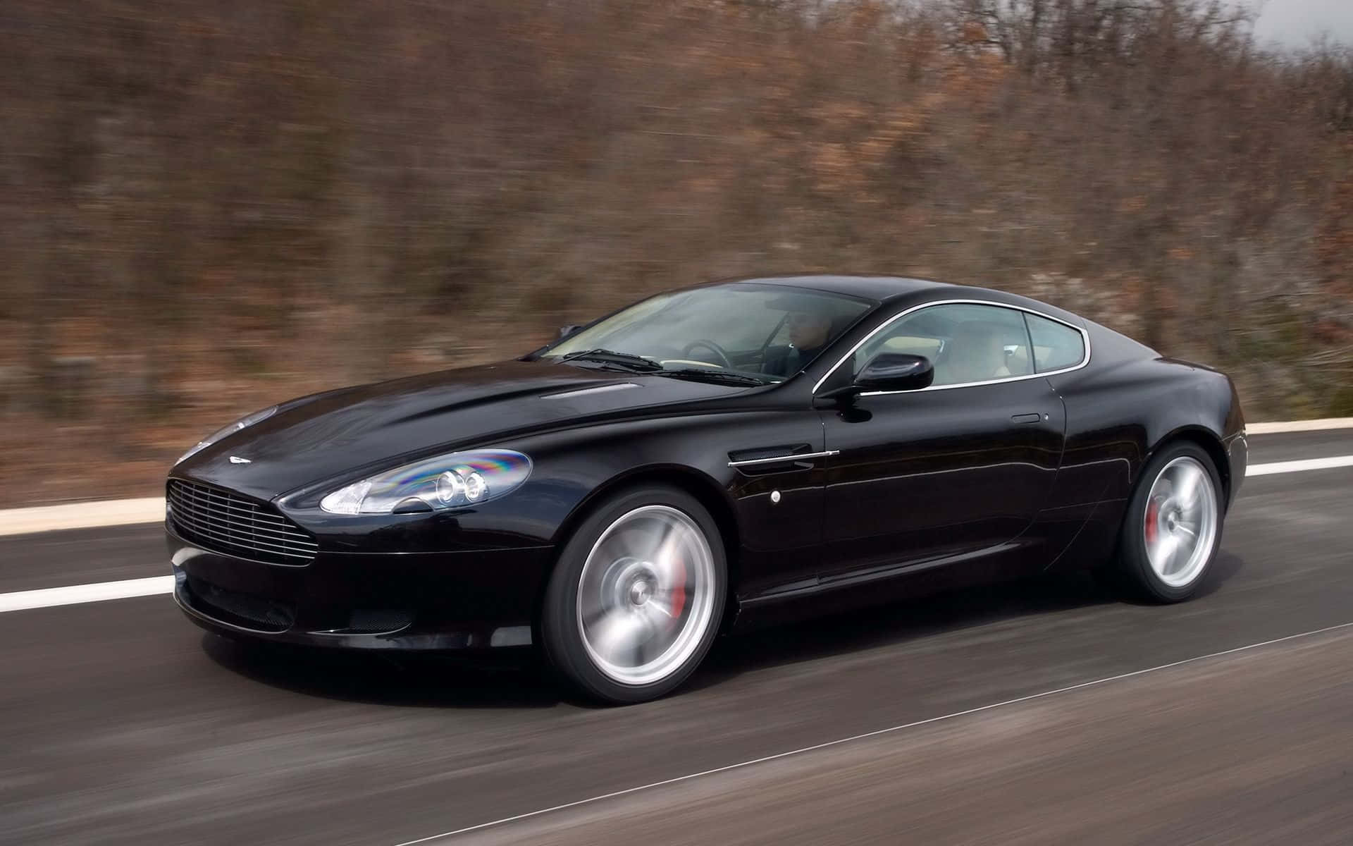 Eleganteng Aston Martin DB9 sa isang bukas na daan Wallpaper
