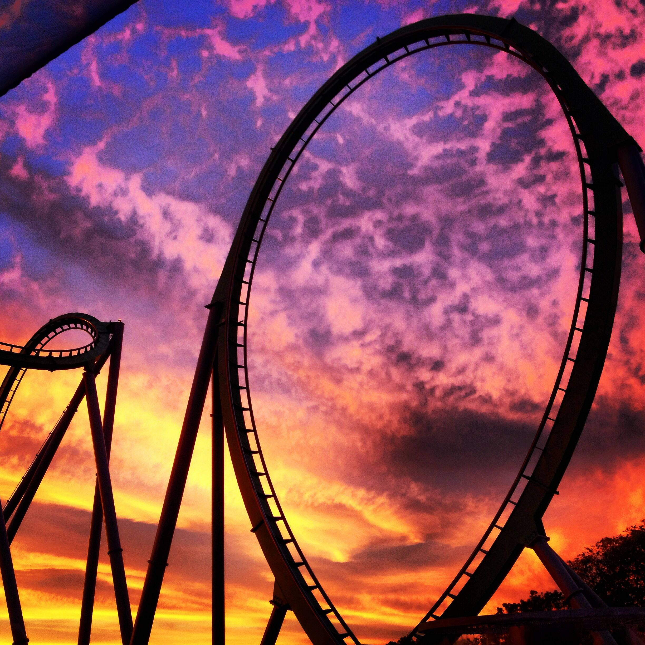 High-Flying Thrill sa Roller Coaster sa gitna ng Vibrant Sunset Wallpaper