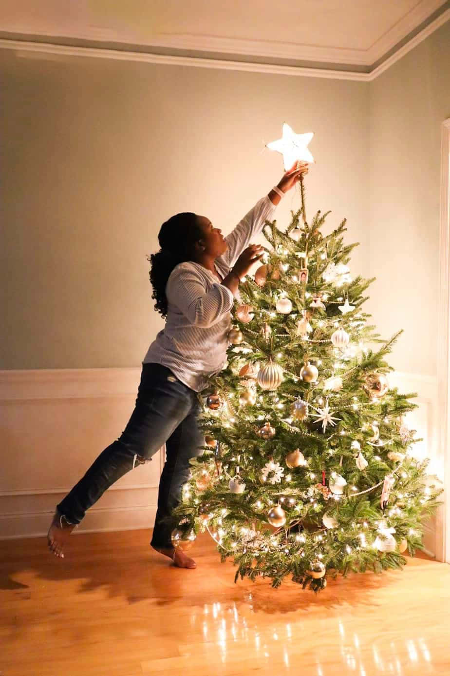Isang babae ang naglalagay ng bituin sa Christmas tree Wallpaper