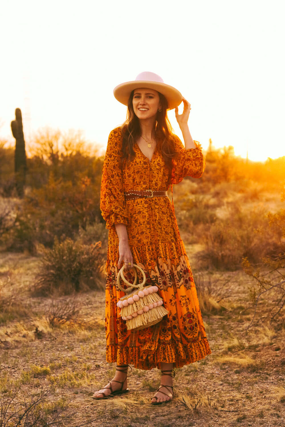 Isang babae na naka-orange na damit at sombrero sa disyerto Wallpaper