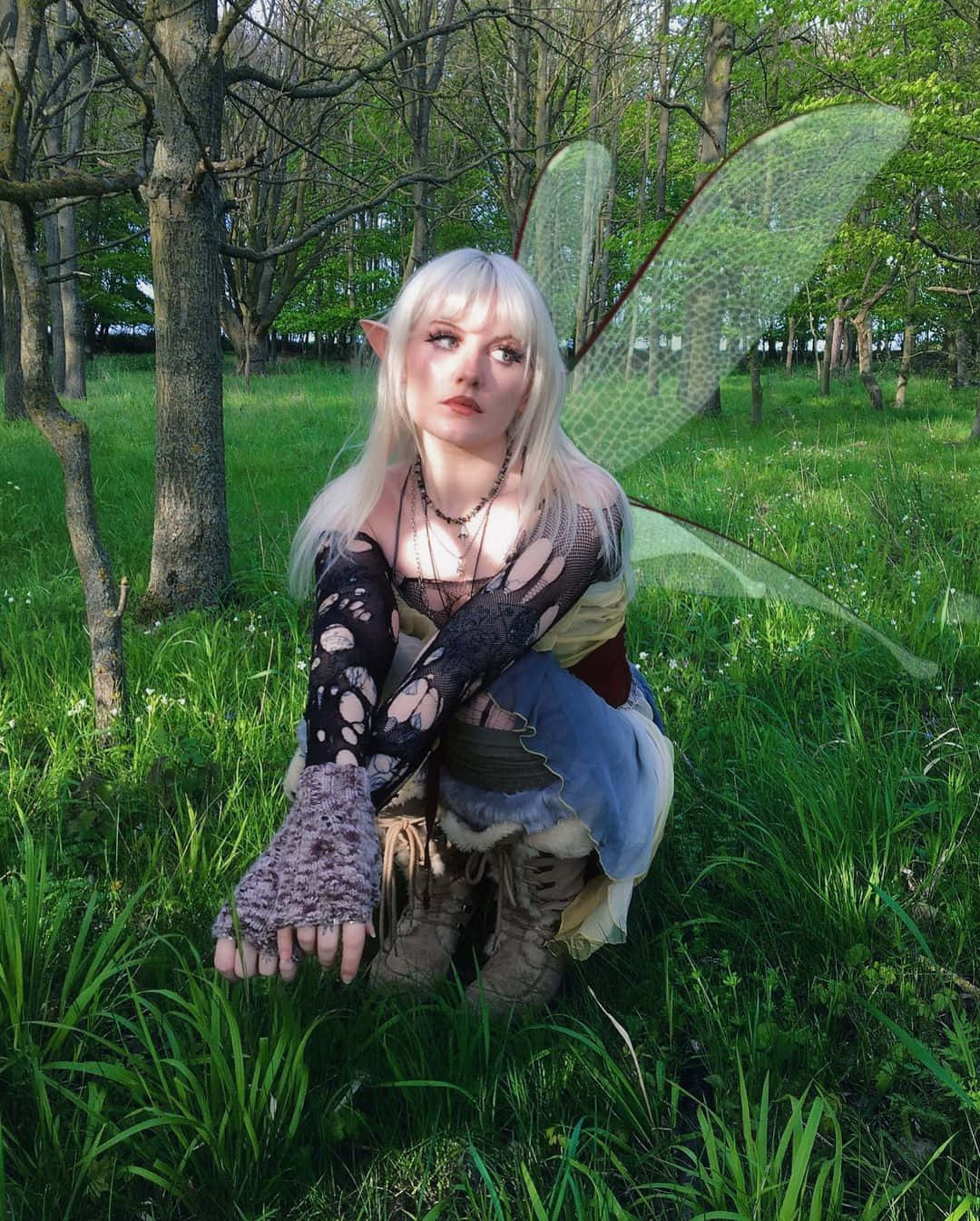isang babae na naka-fairy costume na nakayuko sa damo Wallpaper