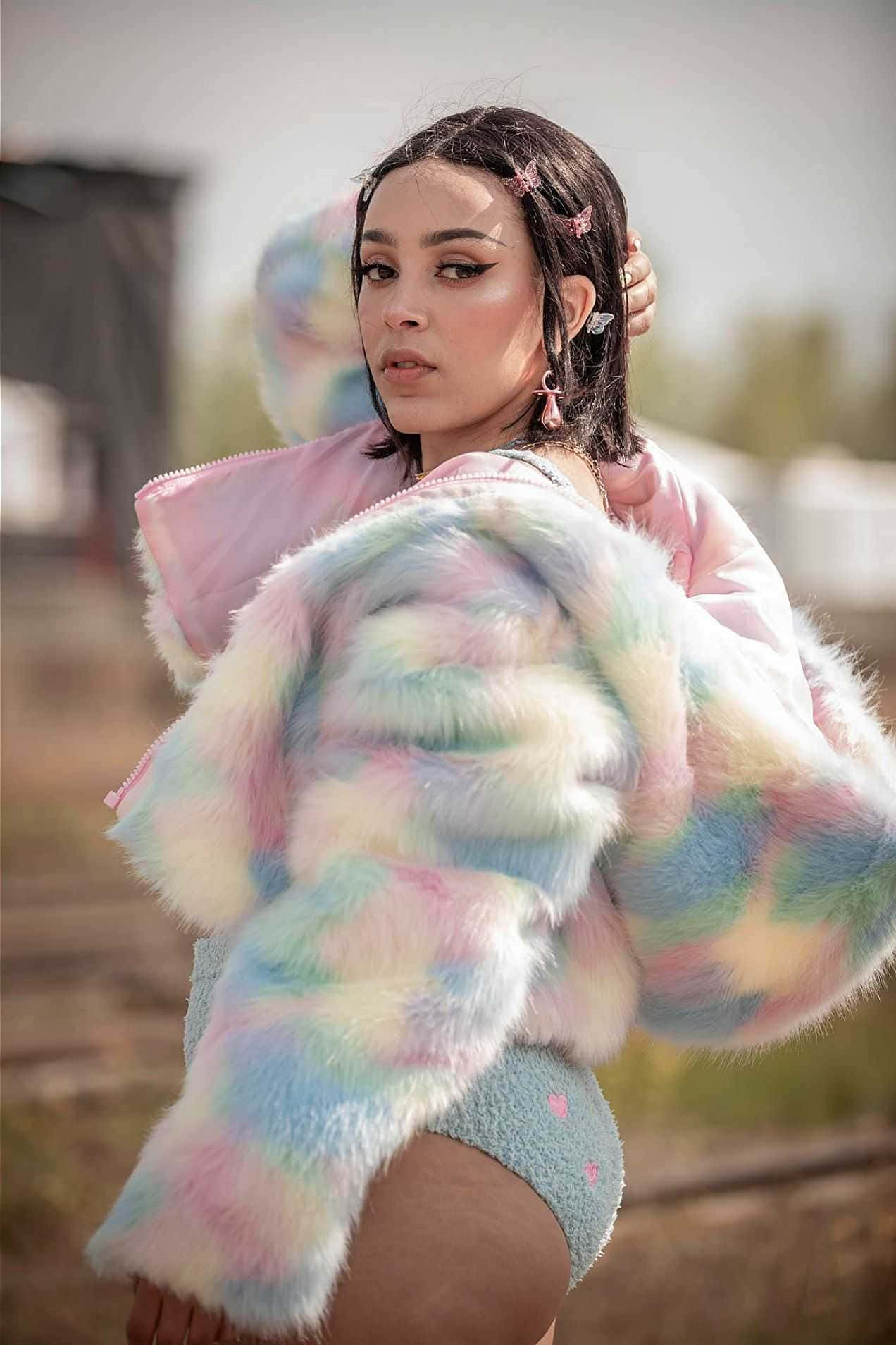 isang babaeng naka-makulay na fur coat na nagpapapose Wallpaper