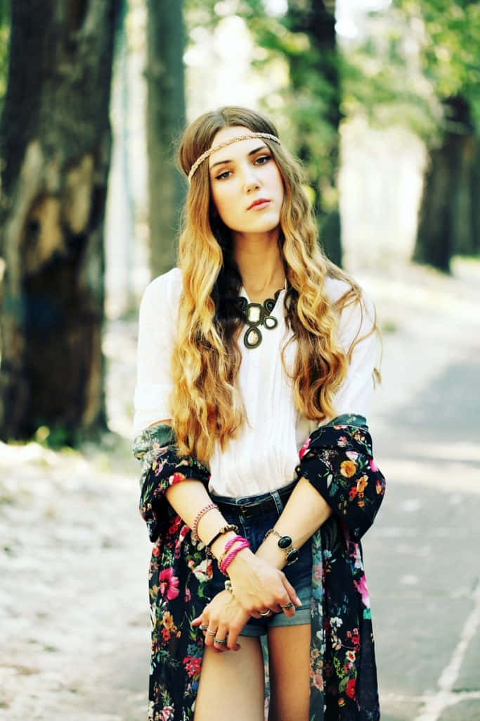 isang batang babae na nakasuot ng floral dress at shorts ay nagpapose sa sidewalk Wallpaper