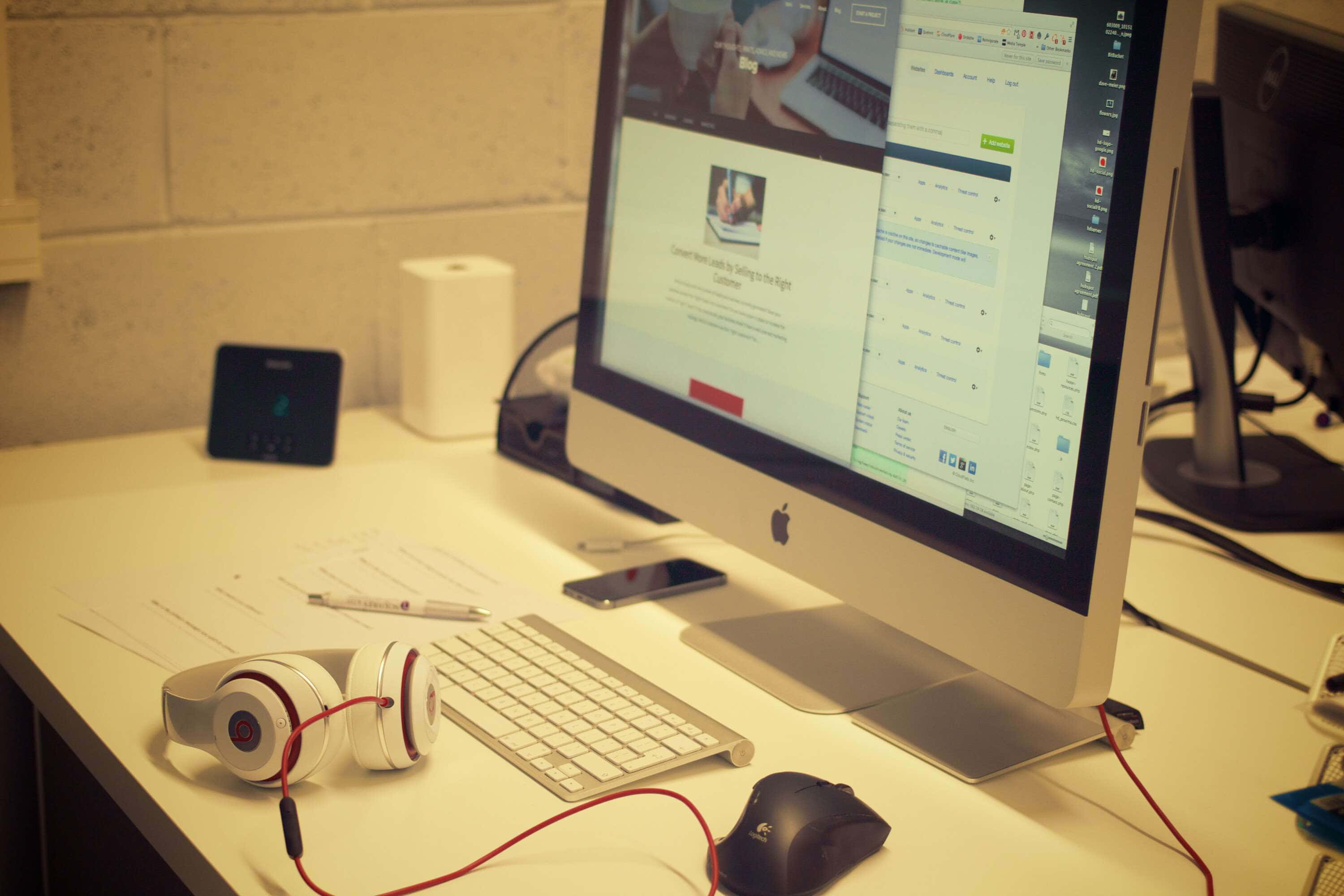 isang computer monitor at headphone sa isang desk Wallpaper
