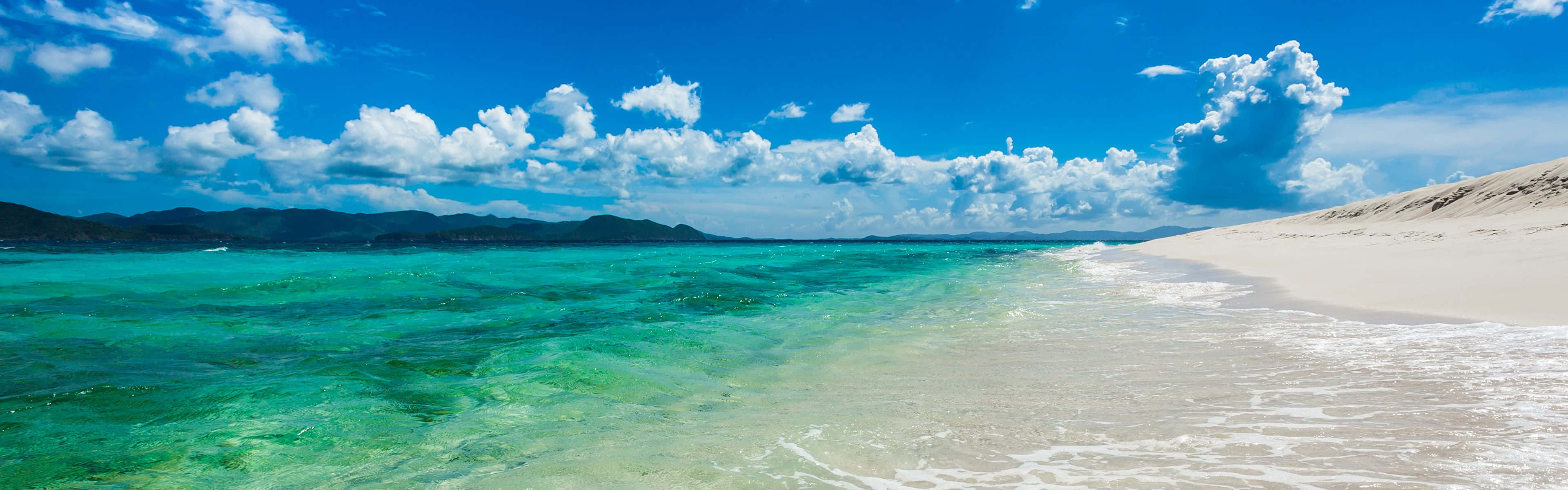 isang dalampasigan na may malinaw na tubig at puting buhangin Wallpaper