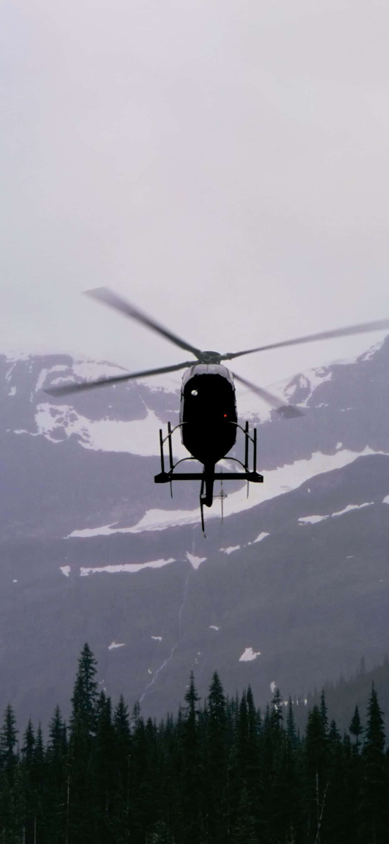 isang helicopter na lumilipad sa ibabaw ng isang kabundukan Wallpaper