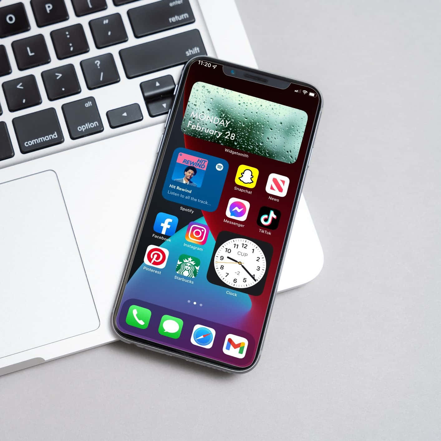 isang iPhone xr na may mga app na nakaupo sa tabi ng isang laptop Wallpaper