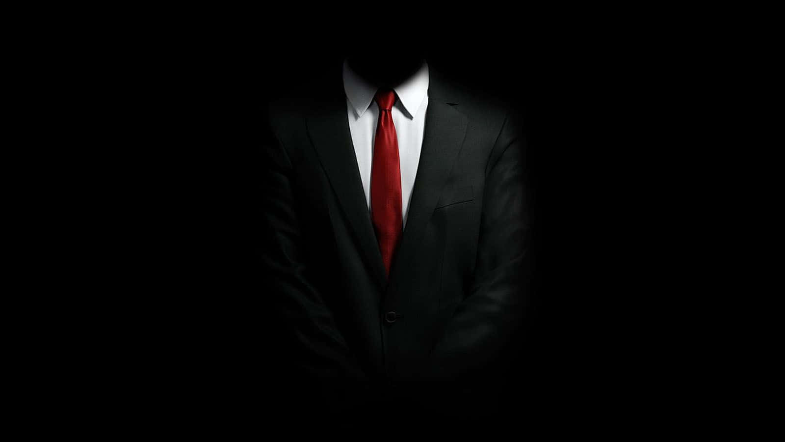 Isang lalaking naka-suit at kurbata ang nakatayo sa dilim Wallpaper