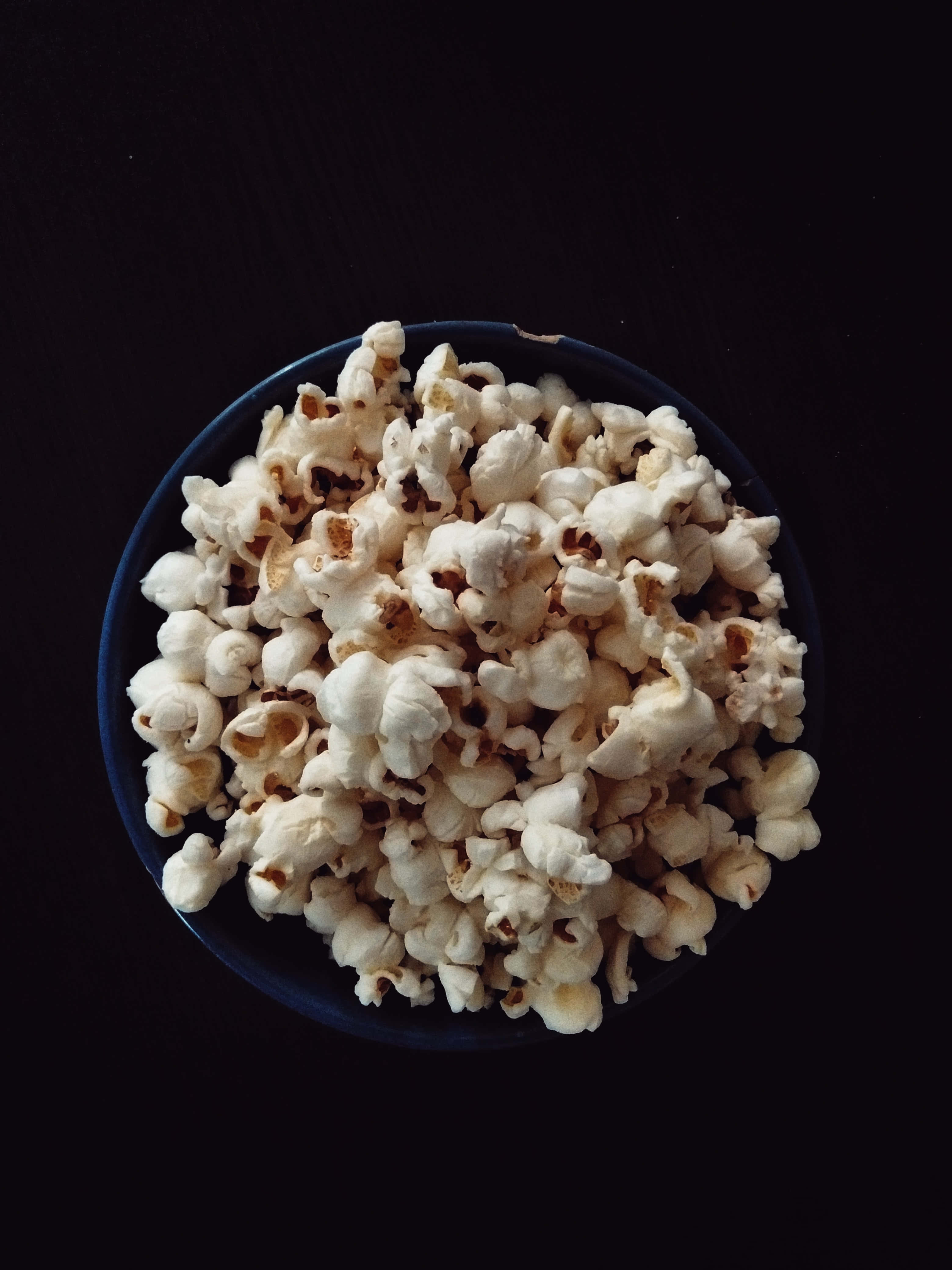 isang mangkok ng popcorn sa isang itim na mesa Wallpaper