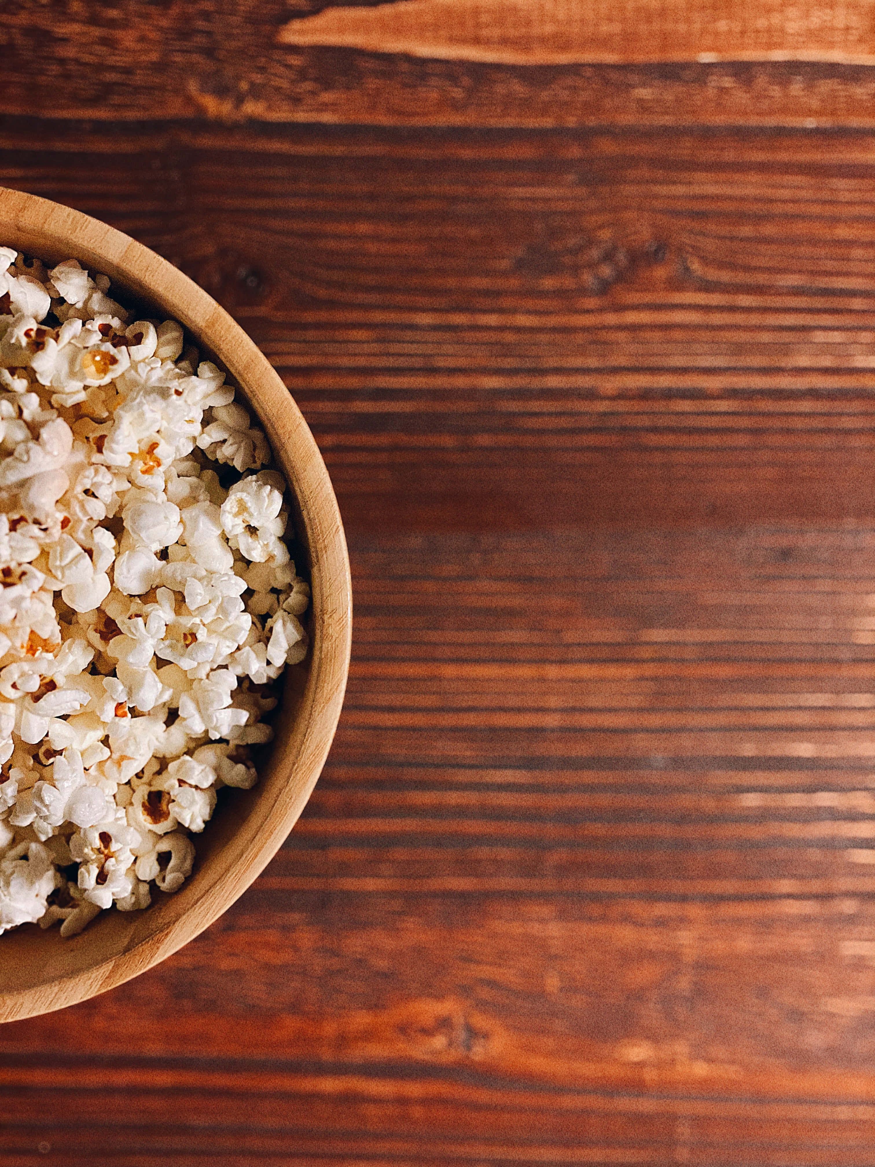 isang mangkok ng popcorn sa isang kahoy na mesa Wallpaper
