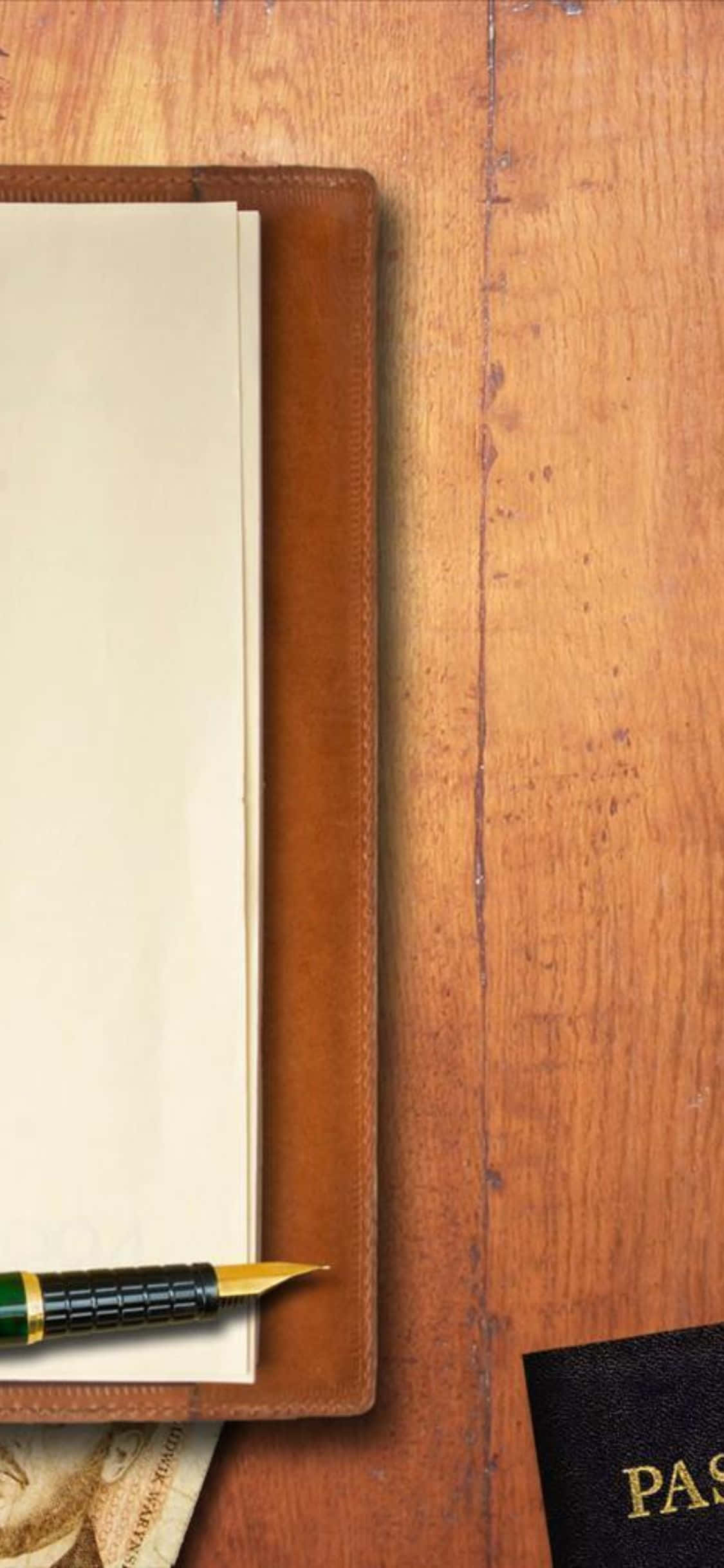 isang passport at panulat sa wooden table Wallpaper