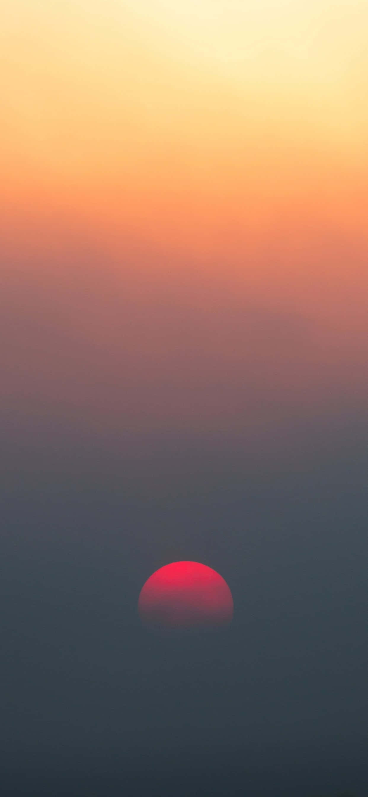 isang pulang araw na bumabangon sa itaas ng isang fog-filled na langit Wallpaper
