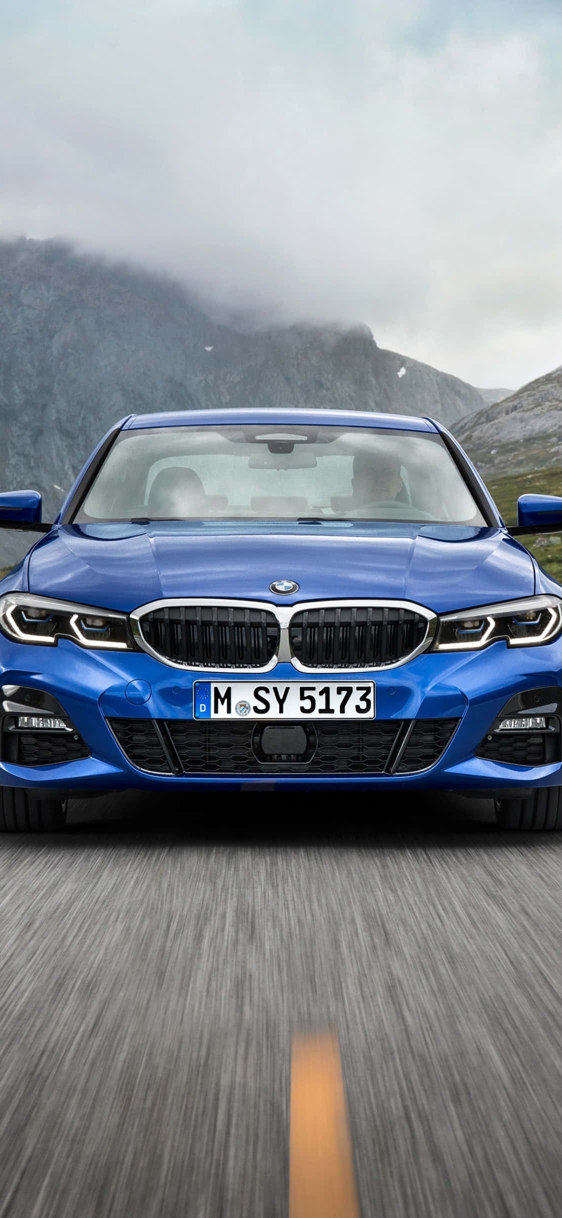 Isang puting BMW X Series na naka-parka sa tabi ng iPhone X Wallpaper