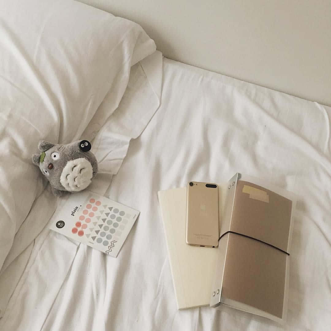isang puting kama na may teddy bear at notebook Wallpaper
