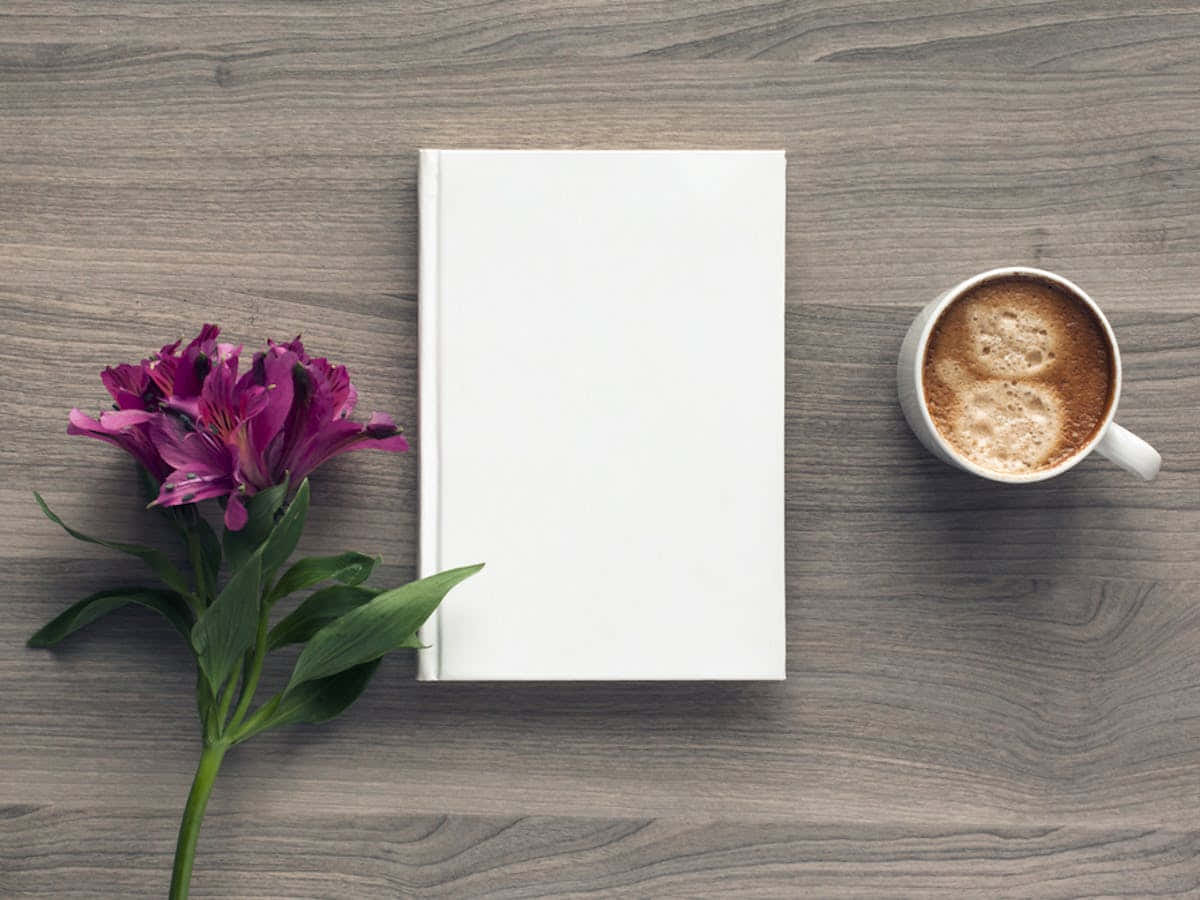 isang puting libro at isang tasa ng kape sa isang kahoy na mesa Wallpaper