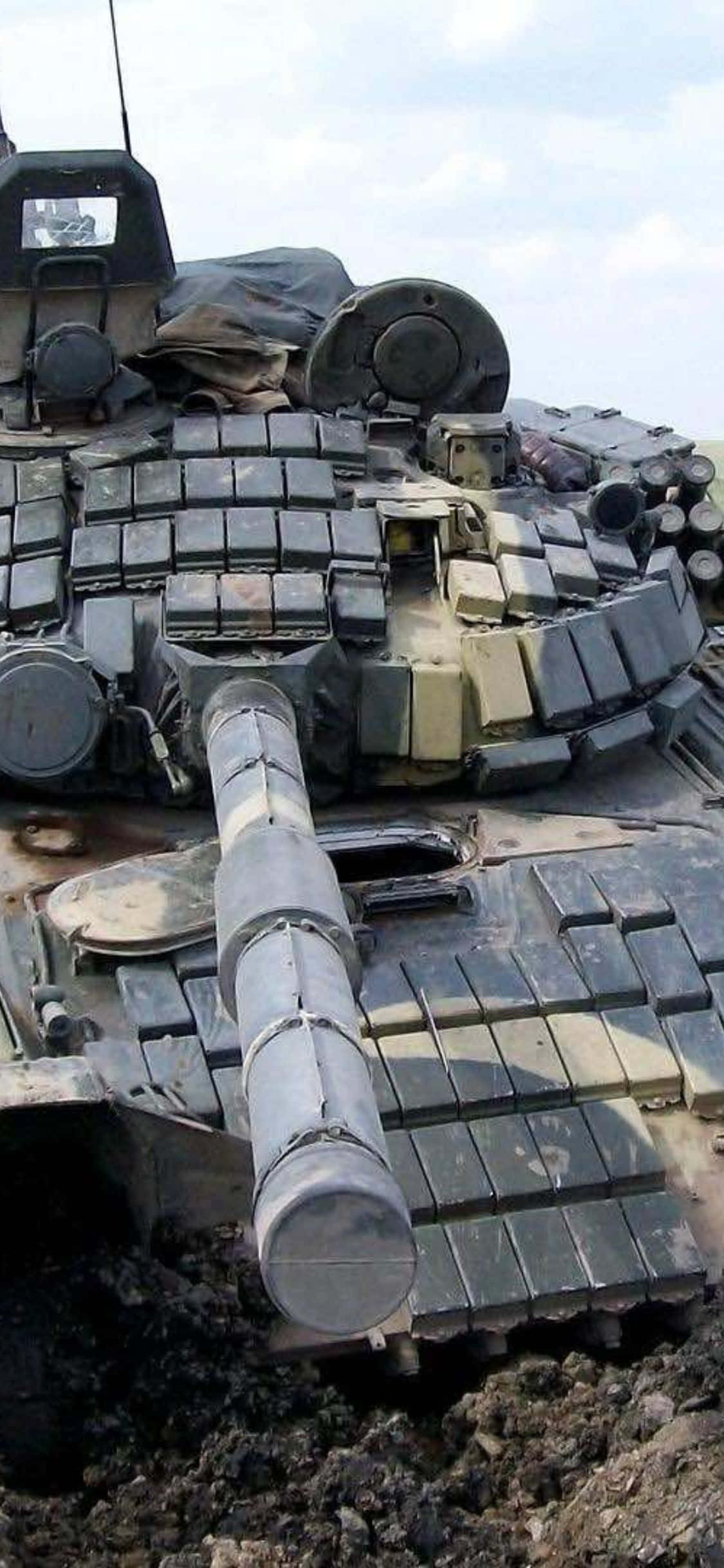 isang tank ay nakaupo sa dumi na may malaking bilang ng mga piraso ng kagamitan Wallpaper
