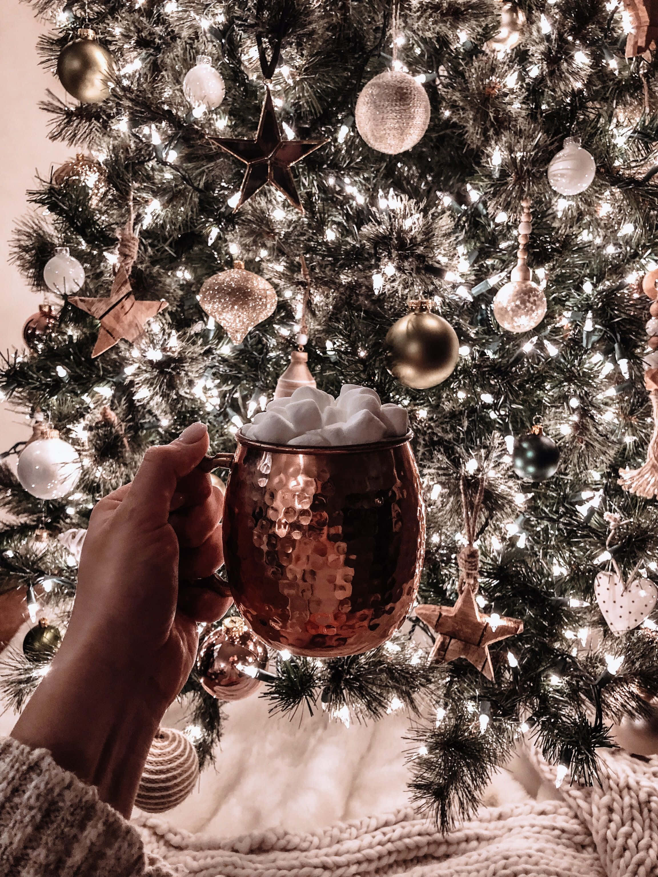 isang tao na may hawak na tasa ng kape sa harap ng christmas tree Wallpaper