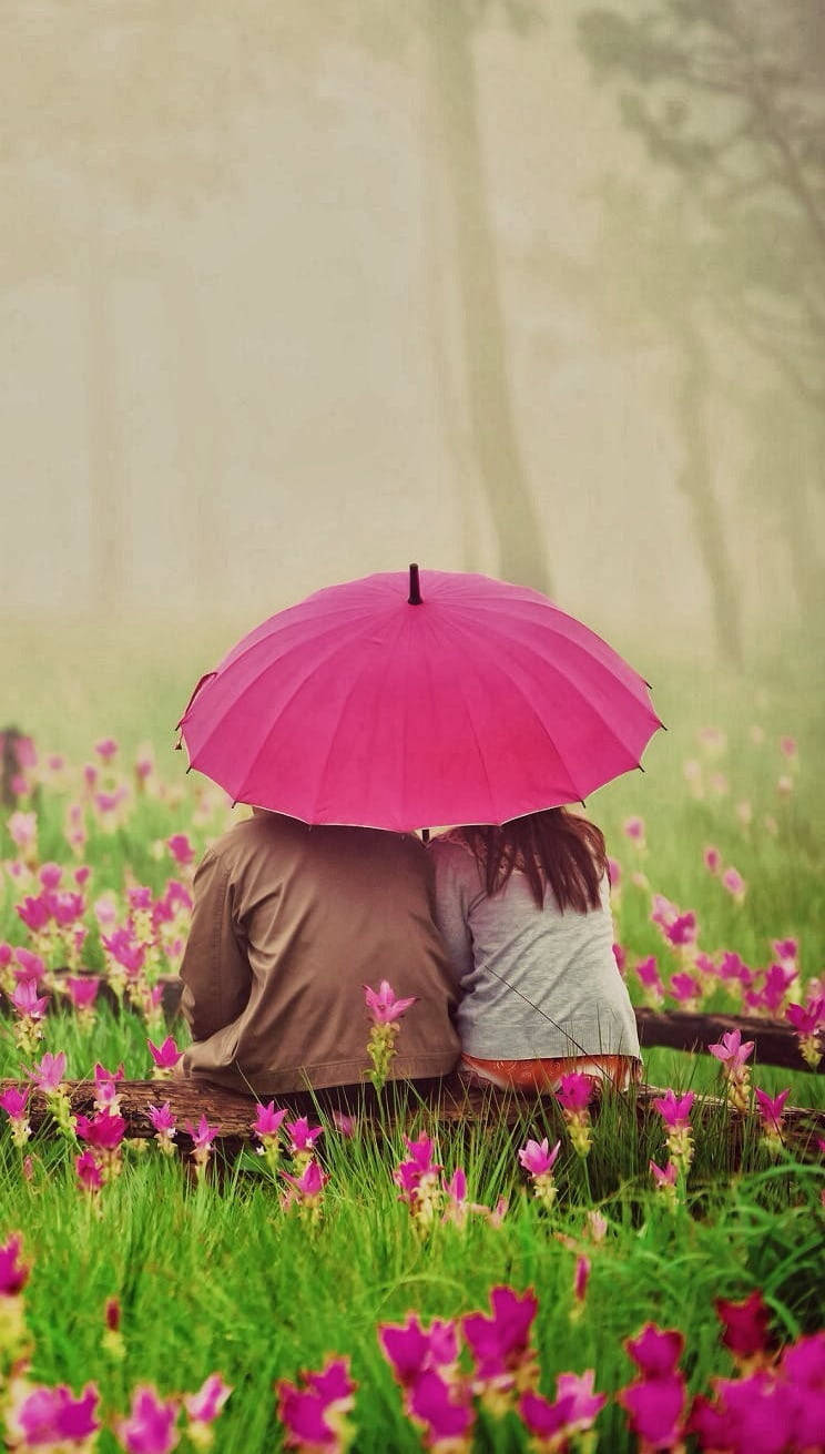 Magkasintahan na may Payong sa Hardin ng mga Bulaklak Wallpaper
