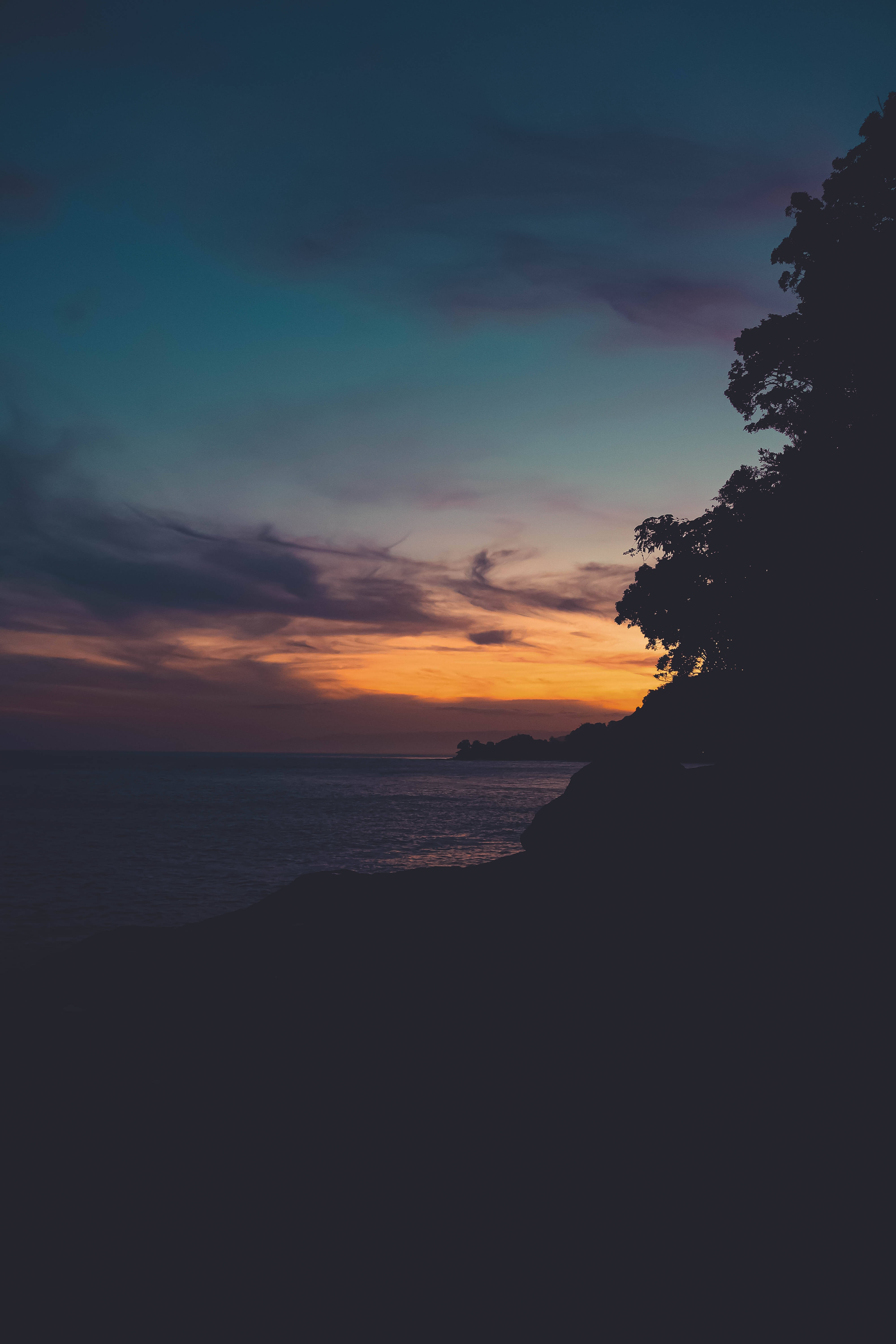 Matingkad na kulay pula at kahel ang nagliliwanag sa isang payapang tanawin sa paglubog ng araw Wallpaper