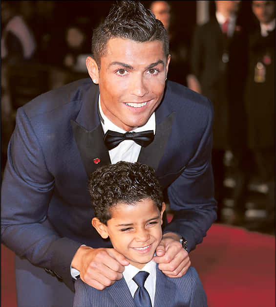 Nakangiting Cristiano Ronaldo Kasama ang Bata sa Isang Event Wallpaper