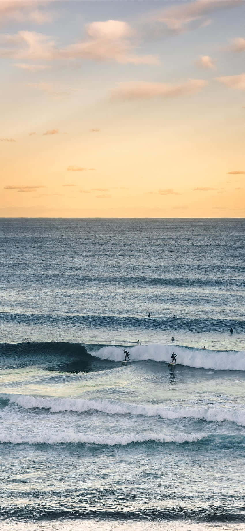 Saluhin ang Alon - Isang surfer na sumasakay sa alon sa karagatan habang ginagamit ang kanilang iPhone Wallpaper