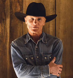 Isang portrait photo ni Ed Harris bilang Virgil Cole sa pelikulang Appaloosa na suot ang kanyang itim na cowboy hat at asul na long-sleeve shirt. — Galaxy Z Flip 8 Wallpaper