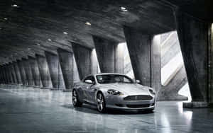 Aston Martin DB9 na Naglalayag sa Isang Scenic Cityscape — MacBook Pro M1 Wallpaper