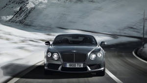 Bentley speeding in snowy mountains wallpaper