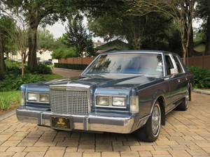Marangal na 1986 Lincoln Town Car na naka-park sa isang sementadong driveway — Cool na mga sasakyan GIF Wallpaper