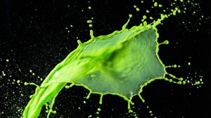Pagsabog ng neon green na likido sa itim.
