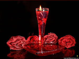 Pulang mga rosas na gawa sa tela na pumapaligid sa isang matataas na pulang kandila sa salamin para sa dekorasyon ng date ng Araw ng mga Puso. — 4:3 Wallpaper