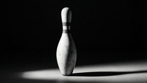 Isang dramatiko na naiilawan na nag-iisang bowling pin sa high-contrast black and white.