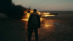 Si Tom Hardy bilang Farrier sa Dunkirk pelikula ay tumitig sa isang nasusunog na eroplano wallpaper.