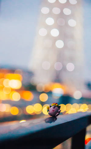 Pokemon Jigglypuff toy atop a balcony in city light backdrop wallpaper. — Redmi Pad 2 Wallpaper