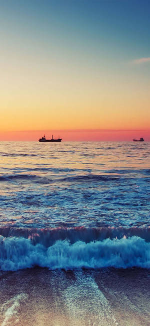 Dagat na may mga alon na sumasabog sa sunset para sa iPhone XR na wallpaper